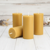 Four yellow candles on a white wooden surface with a light background