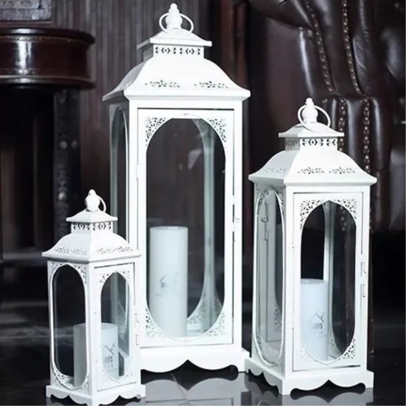 Set of three white decorative lanterns with candles inside on a dark background