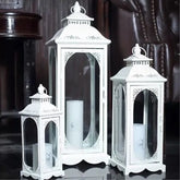 Set of three white decorative lanterns with candles inside on a dark background