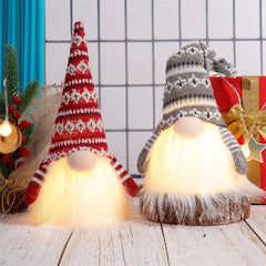 Two lit gnomes with festive hats on a wooden surface with a grid background