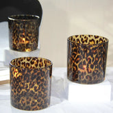 Three leopard print candle holders on a white surface with a neutral background