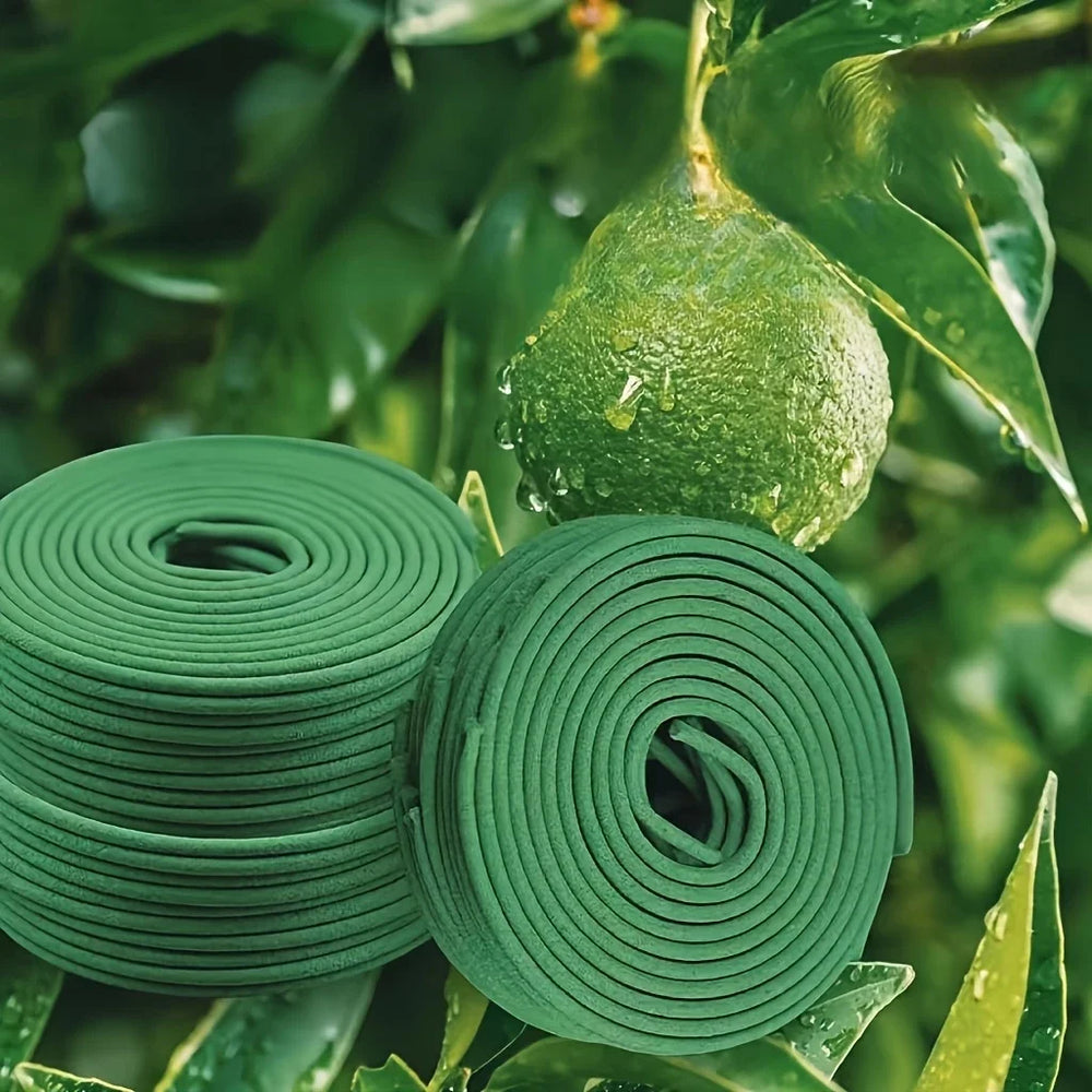 Two rolls of green garden tape on a leafy background with a green fruit.