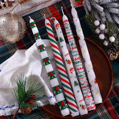 Set of Christmas-themed candles on a decorative table with festive decorations.