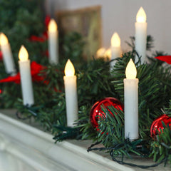 Decorative Christmas garland with candles and red ornaments on a mantelpiece.