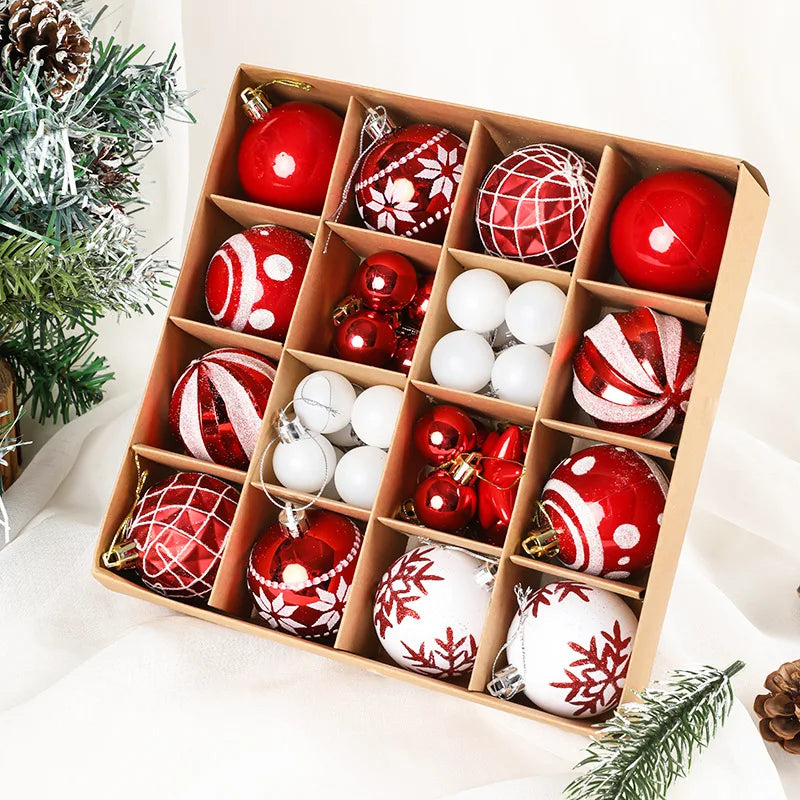 Box of red and white Christmas ornaments on a white surface with greenery.