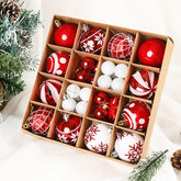 Box of red and white Christmas ornaments on a white surface with greenery.