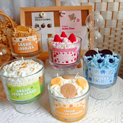Five small glass jars with dessert-themed candles on a textured surface.