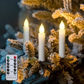 Decorative candles with a remote control on a branch with snow and pine cones.
