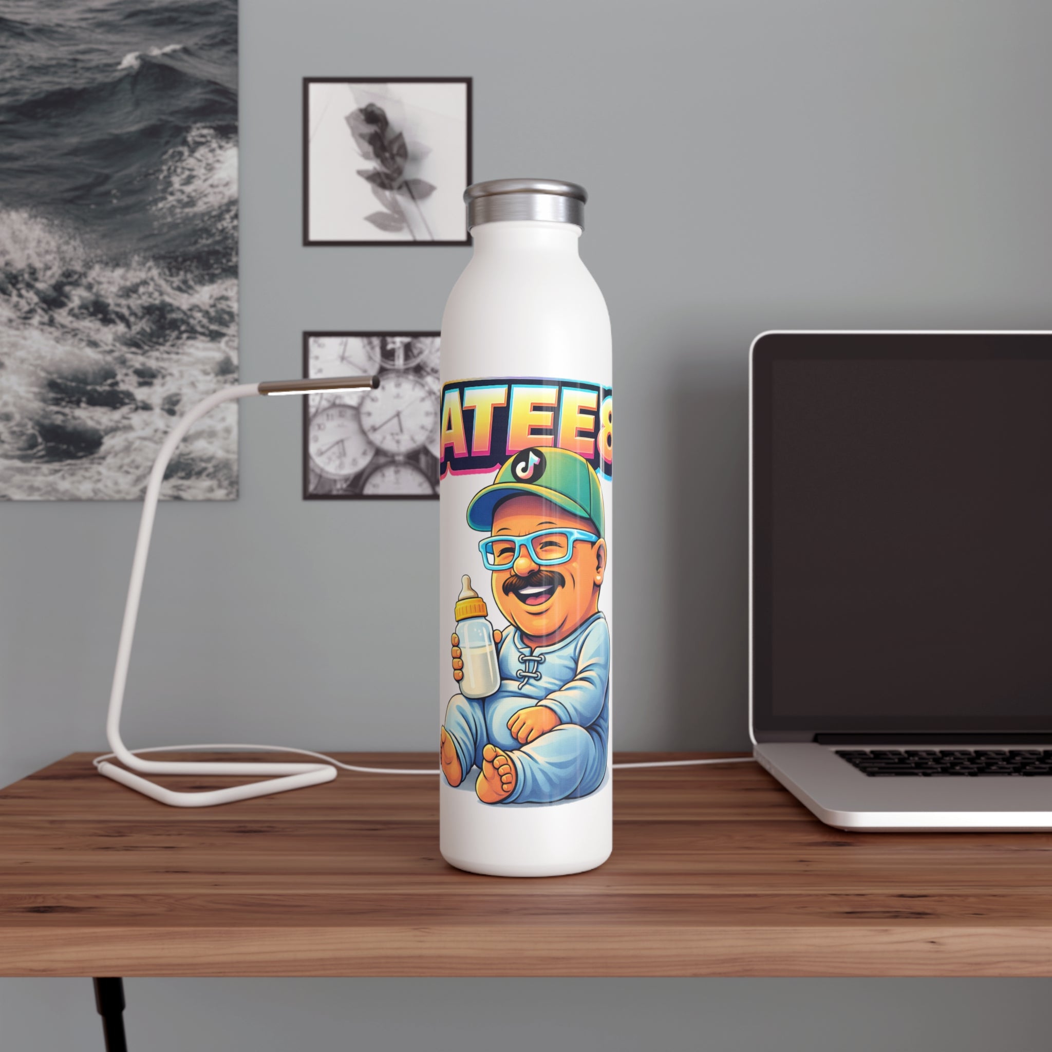 White water bottle with colorful design on a wooden desk with a laptop and lamp.