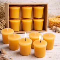 Beeswax candles with a wooden box of candles on a rustic wooden surface.