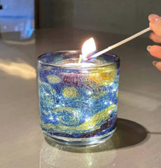 Candle being lit with a match in a glass holder featuring a colorful design.