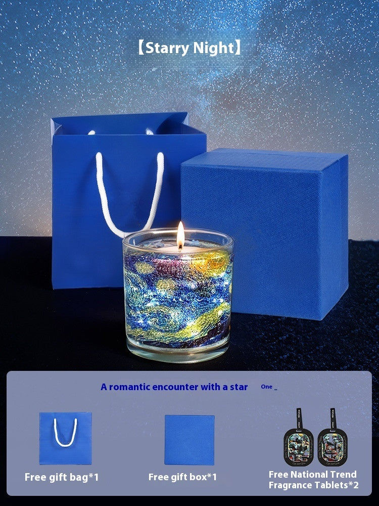 Candle with 'Starry Night' design, blue gift bag, and box on a dark background