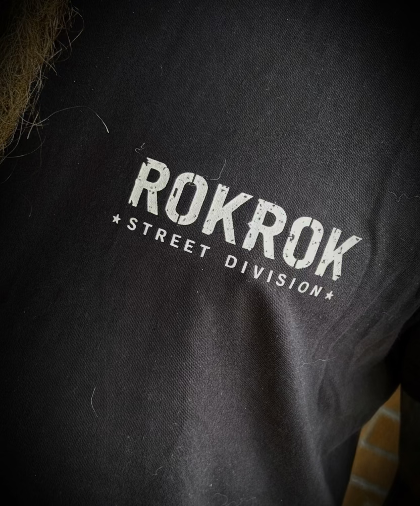 Close-up of a person wearing a black t-shirt with a distressed white graphic that reads 'ROKROK STREET DIVISION'.