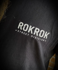 Close-up of a person wearing a black t-shirt with a distressed white graphic that reads 'ROKROK STREET DIVISION'.