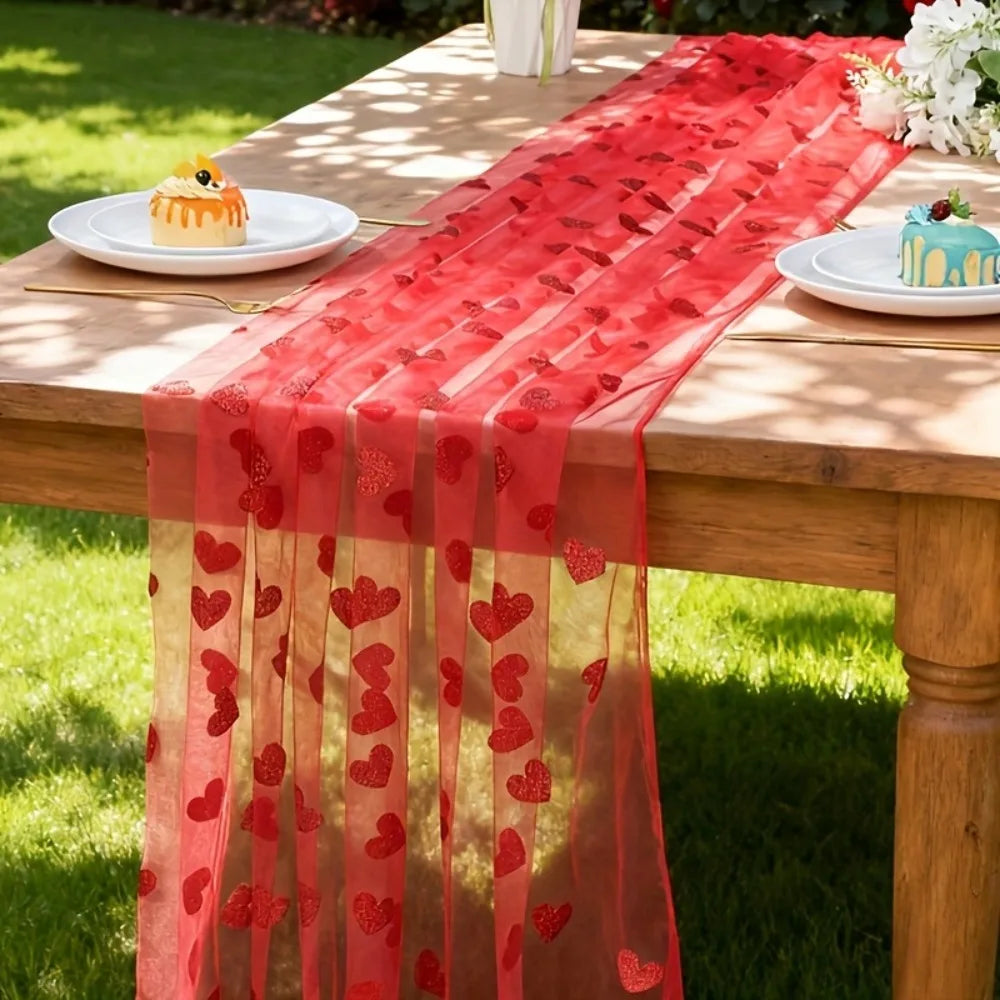 Red heart-patterned table runner on a wooden table outdoors.