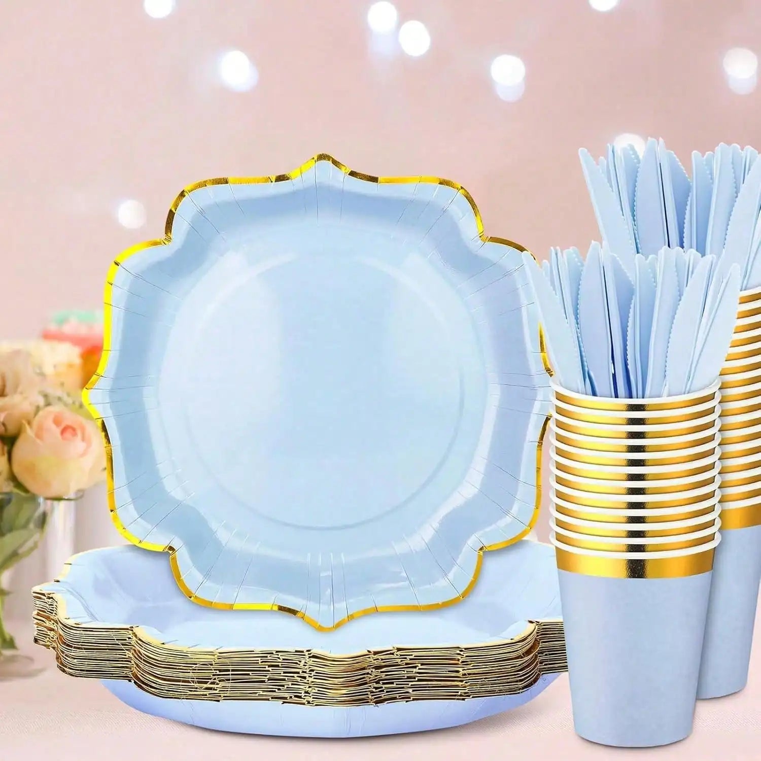 Light blue paper plates with gold trim, cups, and utensils on a pink background.