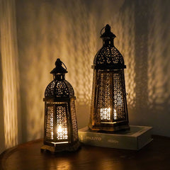 Two illuminated metal lanterns on a wooden surface with a soft background