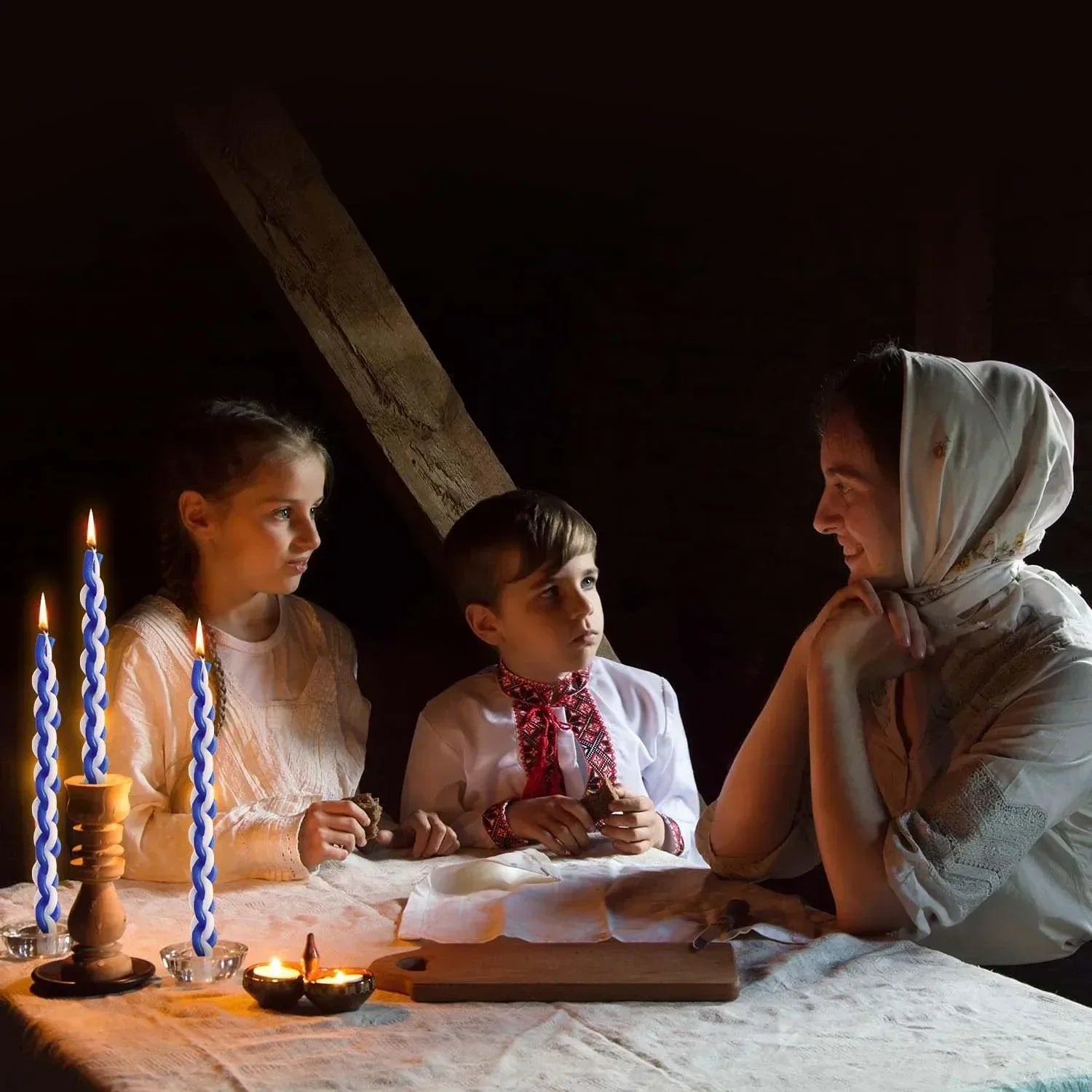 Three people sitting around a table with lit candles in a dimly lit room.