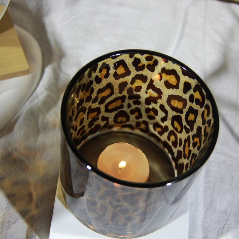 Candle in a leopard print holder on a white surface