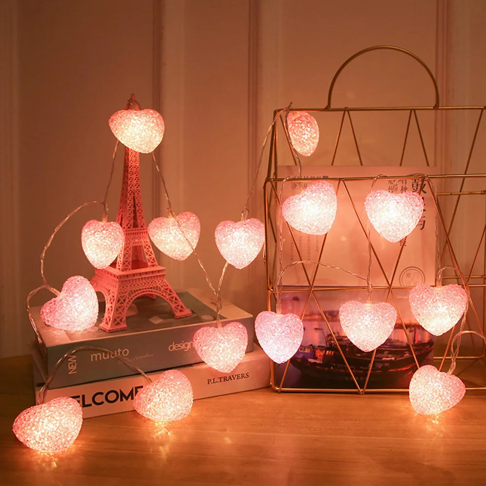 Heart-shaped string lights on a surface with books and decorative items.