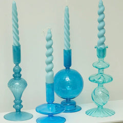 Set of blue glass candle holders with twisted candles on a white surface.