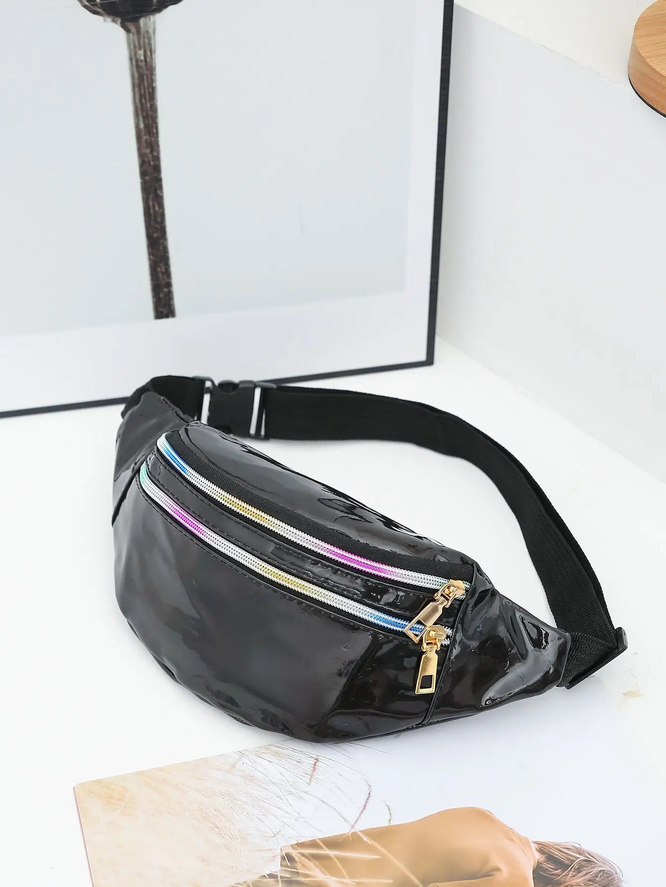 Black fanny pack with colorful zippers on a white surface