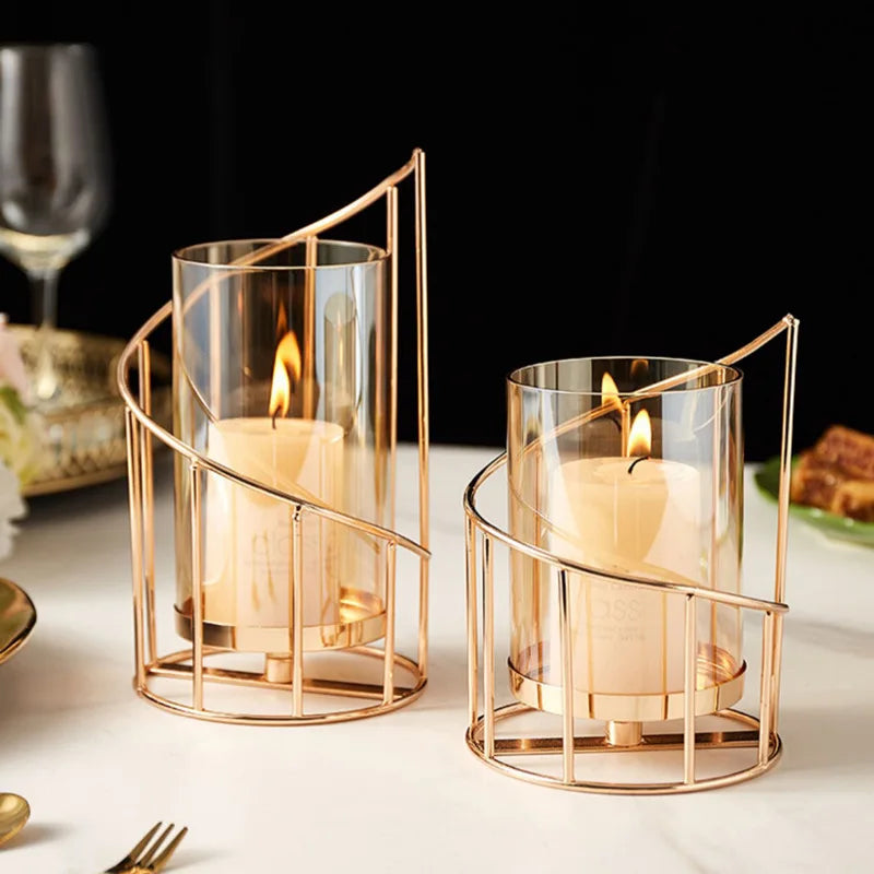 Two gold candle holders with candles on a table setting.