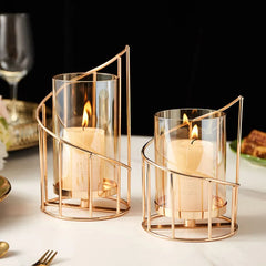 Two gold candle holders with candles on a table setting.