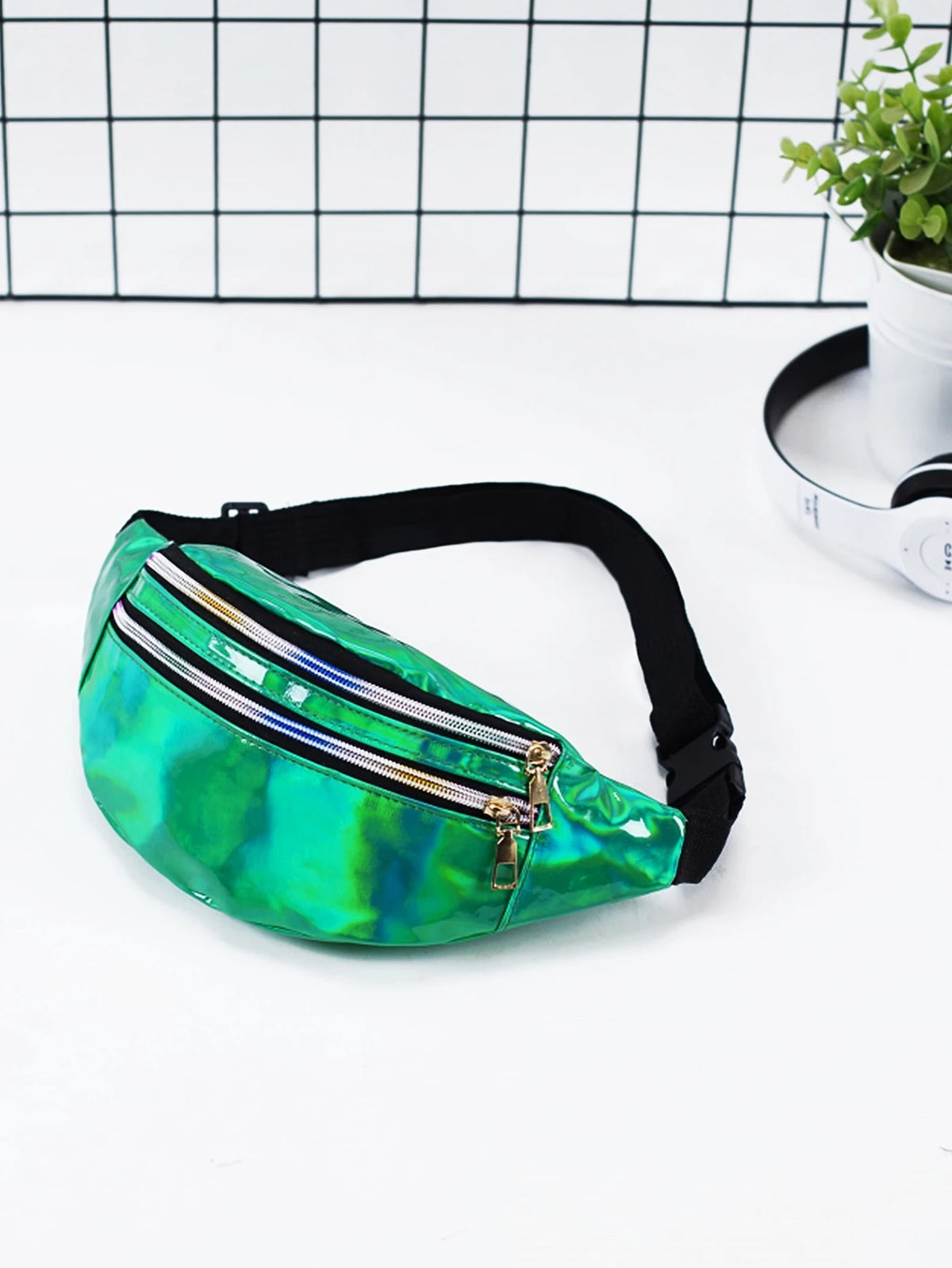 Green and blue transparent fanny pack on a white surface with a grid background