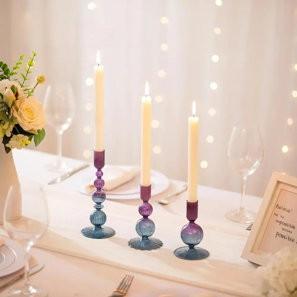 Decorative candlesticks with candles on a table setting with flowers and glasses.
