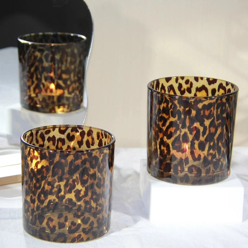Three leopard print candle holders on a white surface with a neutral background