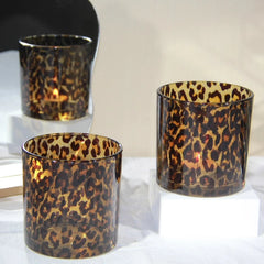 Three leopard print candle holders on a white surface with a neutral background