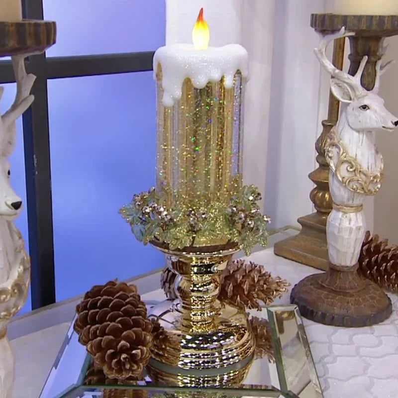 Decorative candle with gold accents and pinecones on a reflective surface.