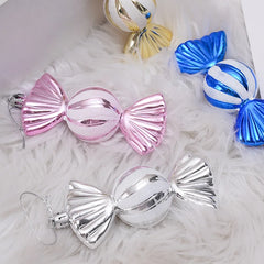 Decorative candy ornaments in pink, blue, and silver on a white surface.
