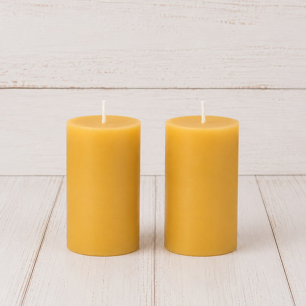 Two yellow candles on a light wooden surface