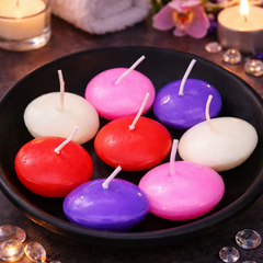 Colorful floating candles in a black bowl on a dark surface with decorative elements.