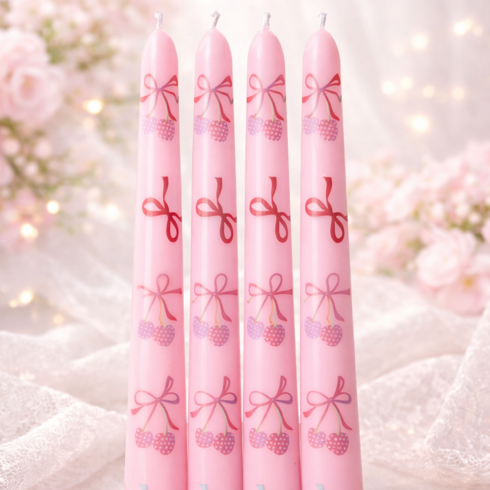 Set of pink candles with decorative bows on a soft background