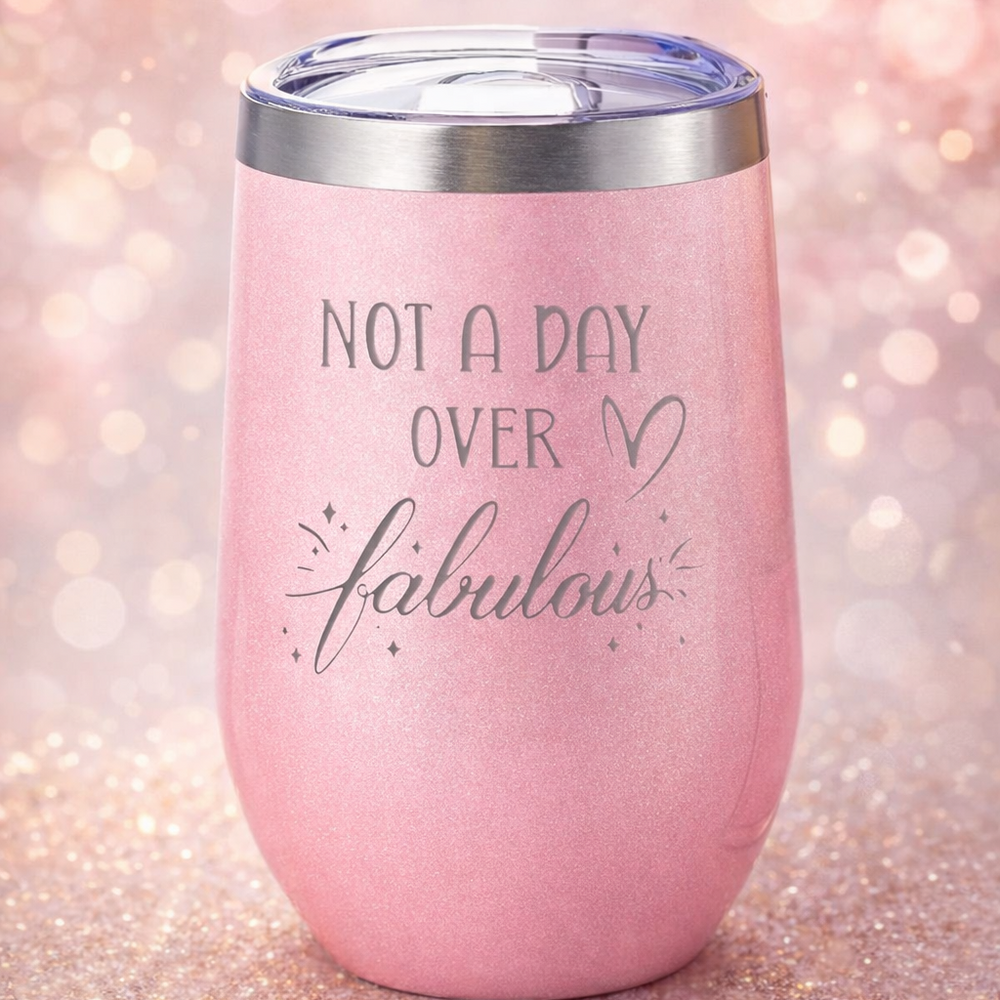 Pink tumbler with 'Not a day over fabulous' text on a glittery background