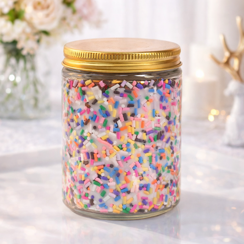 Jar of colorful sprinkles with a gold lid on a light surface with a blurred floral background