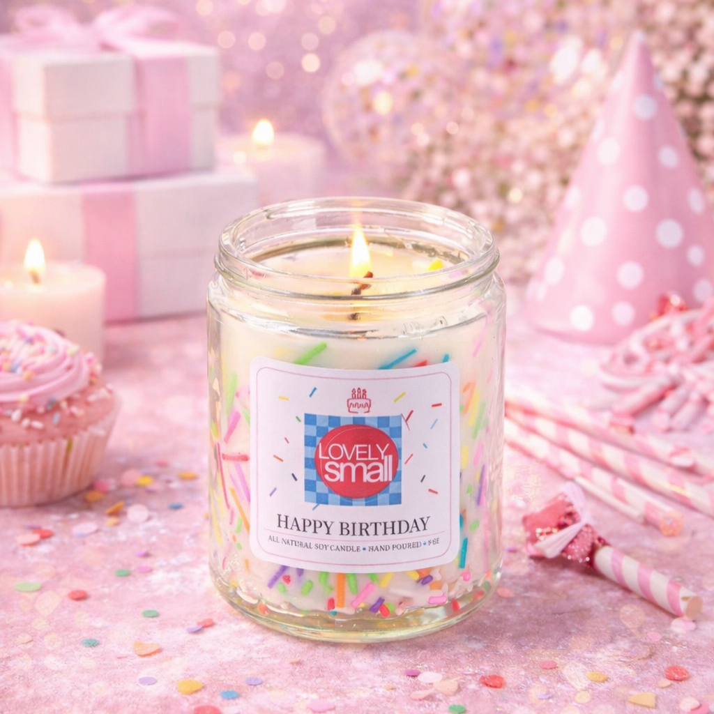 Candle in a glass jar labeled 'Happy Birthday' with a festive background including a party hat and pink decorations.