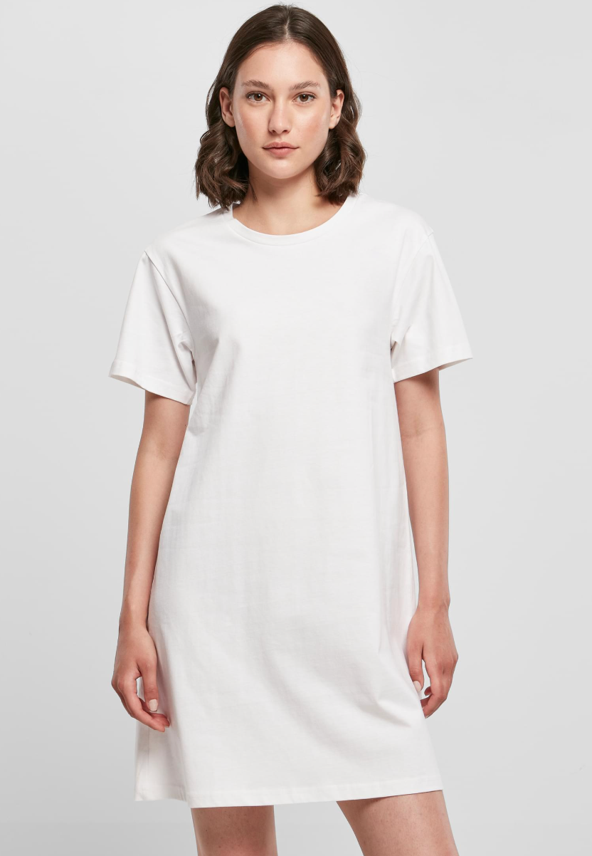 A woman modeling a plain white short-sleeve crewneck t-shirt dress against a light gray studio background.