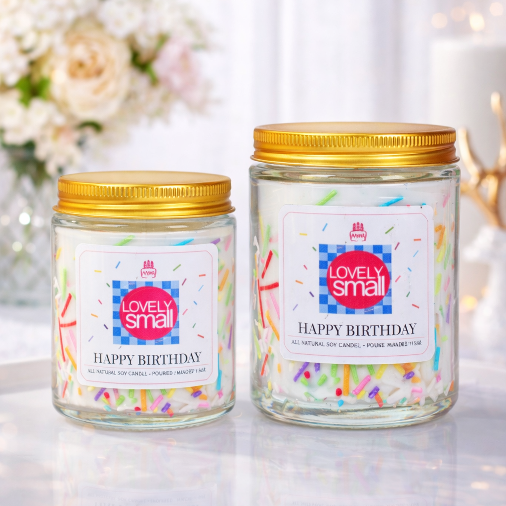 Two 'Lovely Small' birthday candles with gold lids on a decorative surface.