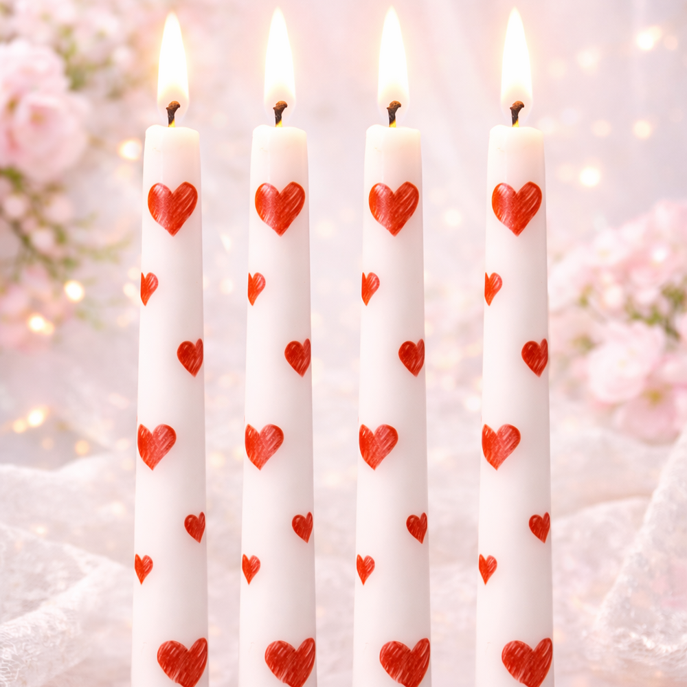 Set of candles with red heart patterns on a blurred floral background